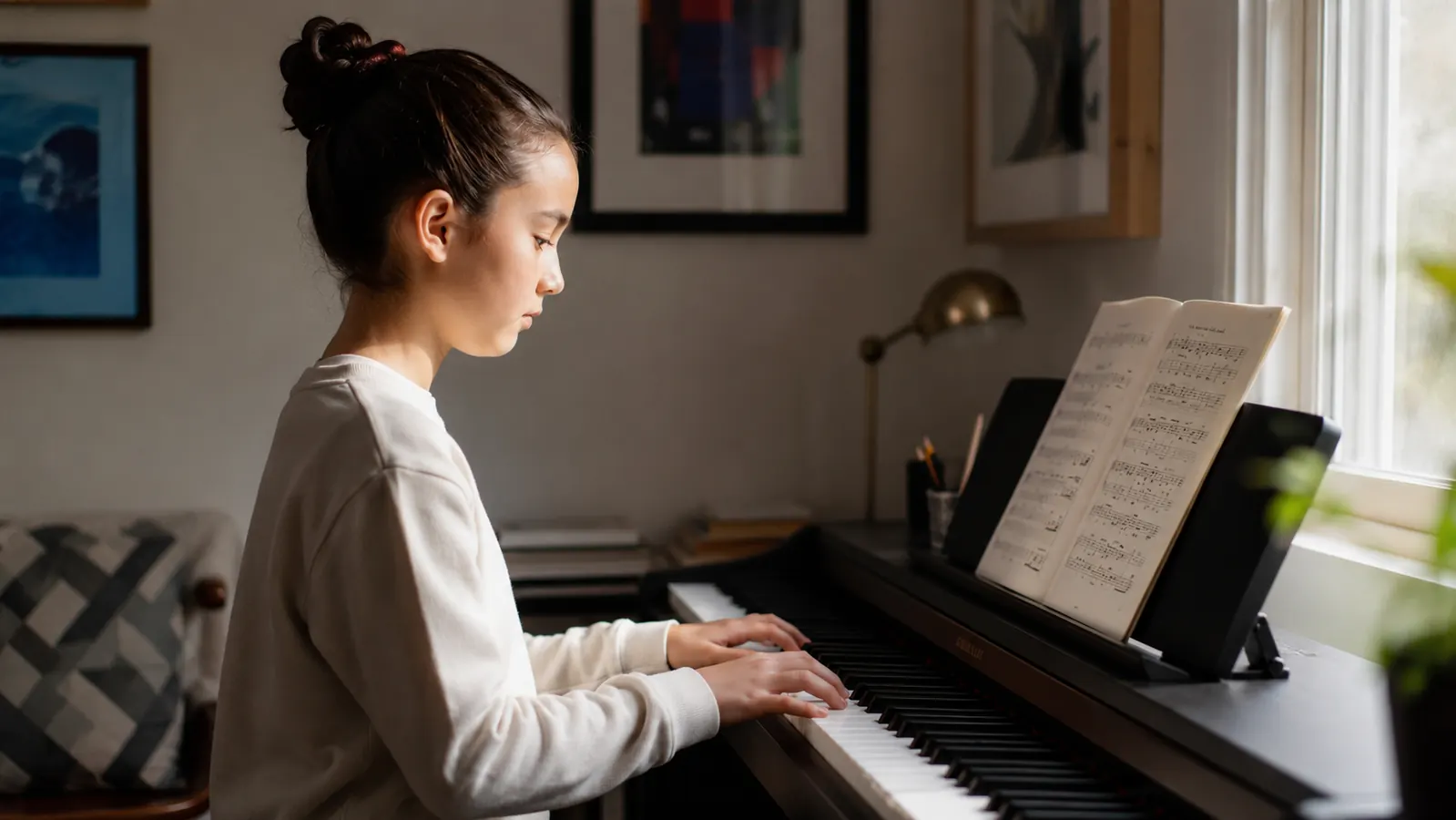 Hands of a young piano student positioned over the keys of an 88-key digital piano, a sheet of method-book music open on the stand